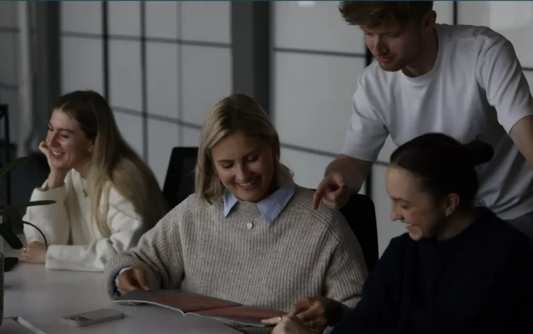 Das Team von der Agentur dasMinisterium sitzt an einem Meetingtisch und schaut sich fröhlich etwas auf dem Laptop an