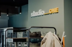 Detailaufnahme eines Bürobereichs mit Regalen und dem Schriftzug ‚studio_one`