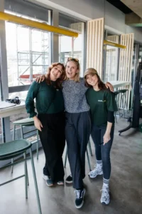 Drei Personen stehen lächelnd zusammen bei einer Eröffnungsveranstaltung.