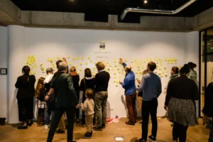 Gruppe von Menschen sammelt Ideen an einer Wand mit Haftnotizen.