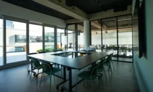 Konferenzraum mit U-förmig angeordneten Tischen und viel Tageslicht.